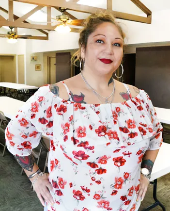 A Divine Women member smiling in a floral blouse